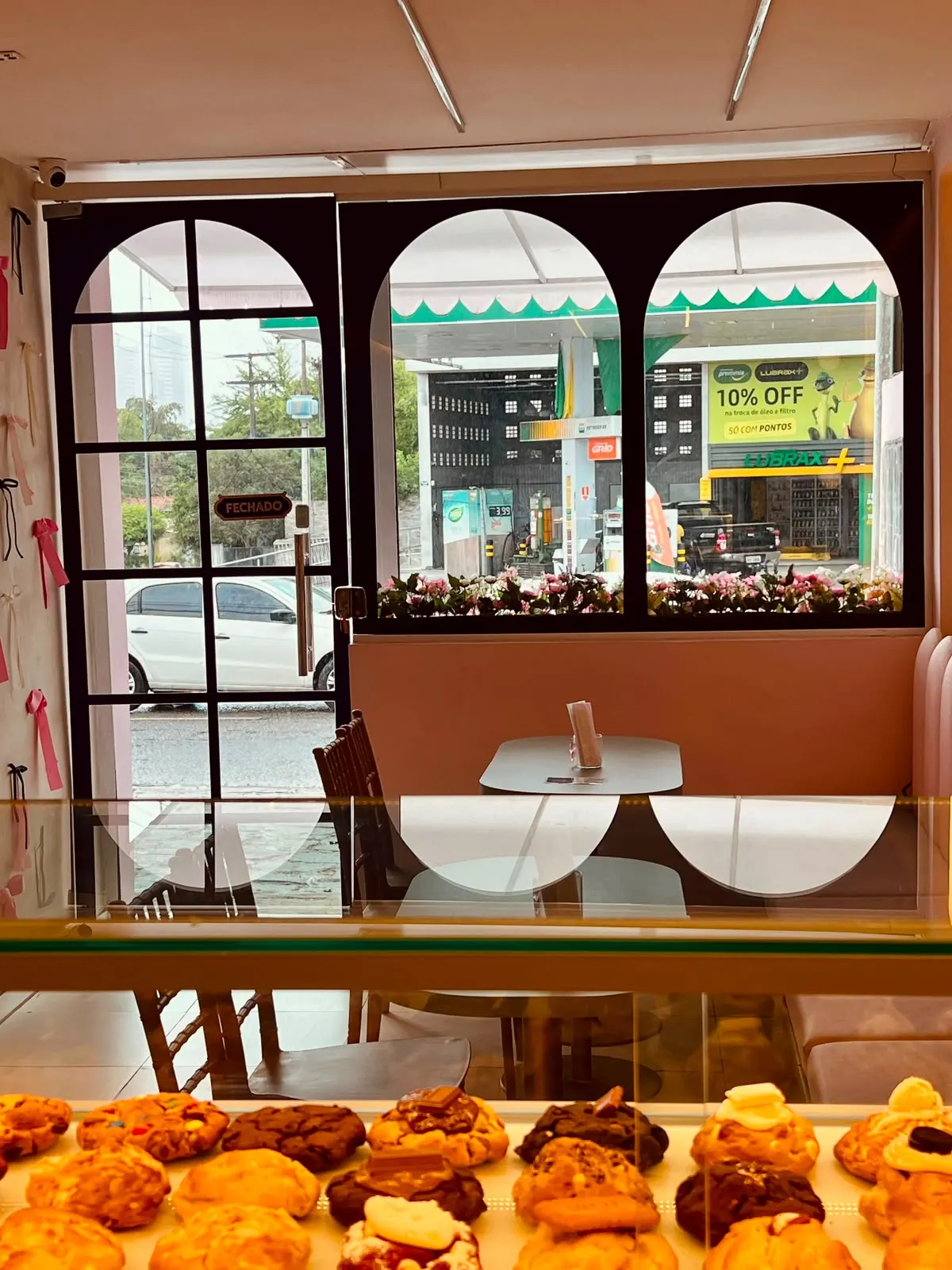 Interior da loja, com a vitrine de cookies e as mesas junto à janela