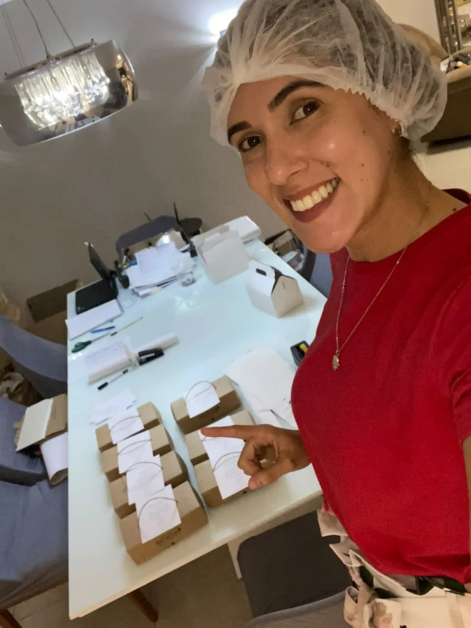 Raullah, cozinheira da Raullah Cookies, segurando um prato de cookies com o avental da marca
